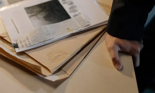 close-up-of-a-hand-reaching-for-papers-on-a-desk