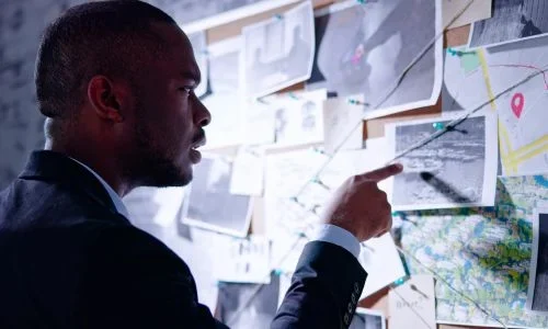 Private investigator a-person-in-a-suit-points-to-a-bulletin-board